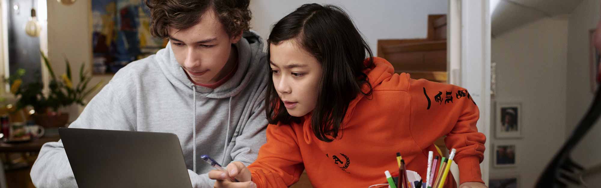 Två tonåringar sitter hemma vid en dator och gör läxor tillsammans